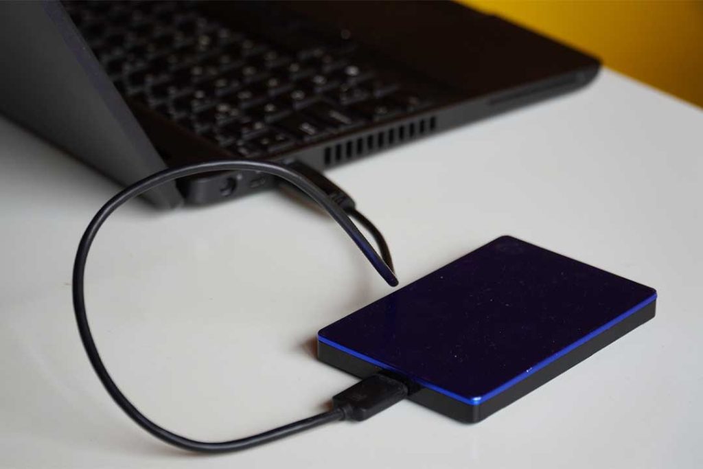 Das Bild zeigt eine externe USB-Festplatte, welche an einem Notebook angeschlossen ist.