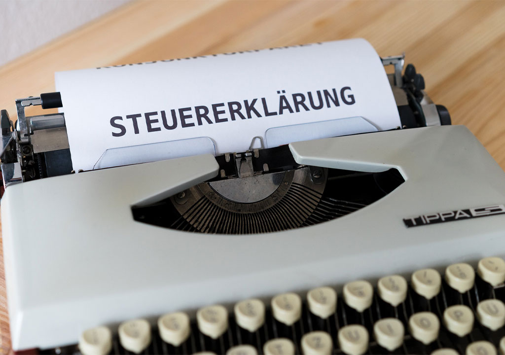 Das Bild zeigt eine Schreibmaschine, in welcher ein Blatt Papier mit dem Schriftzug "Steuererklärung" eingespannt ist.